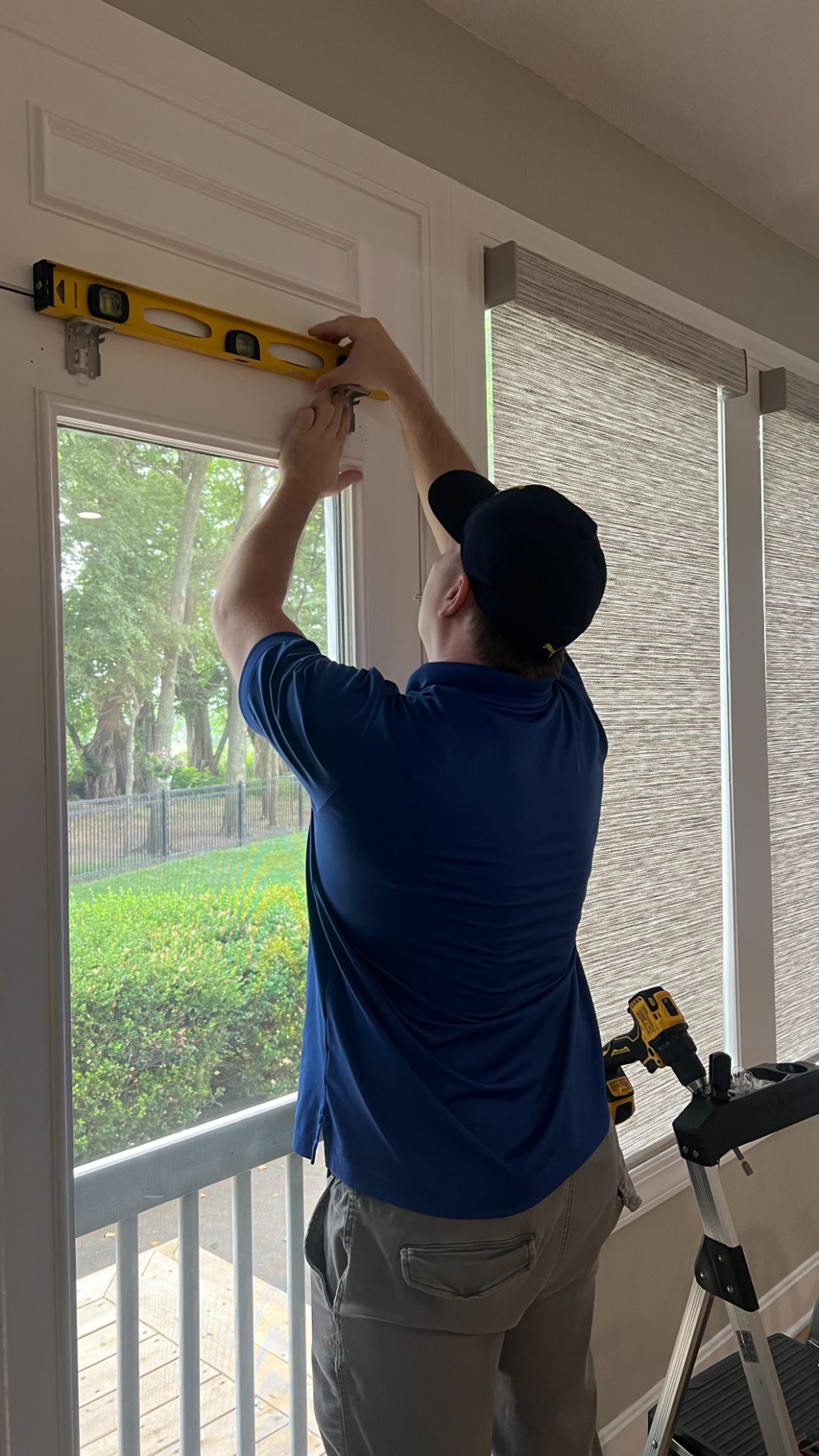 A One Stop Decorating installer using a level to mount Hunter Douglas shades during a professional installation