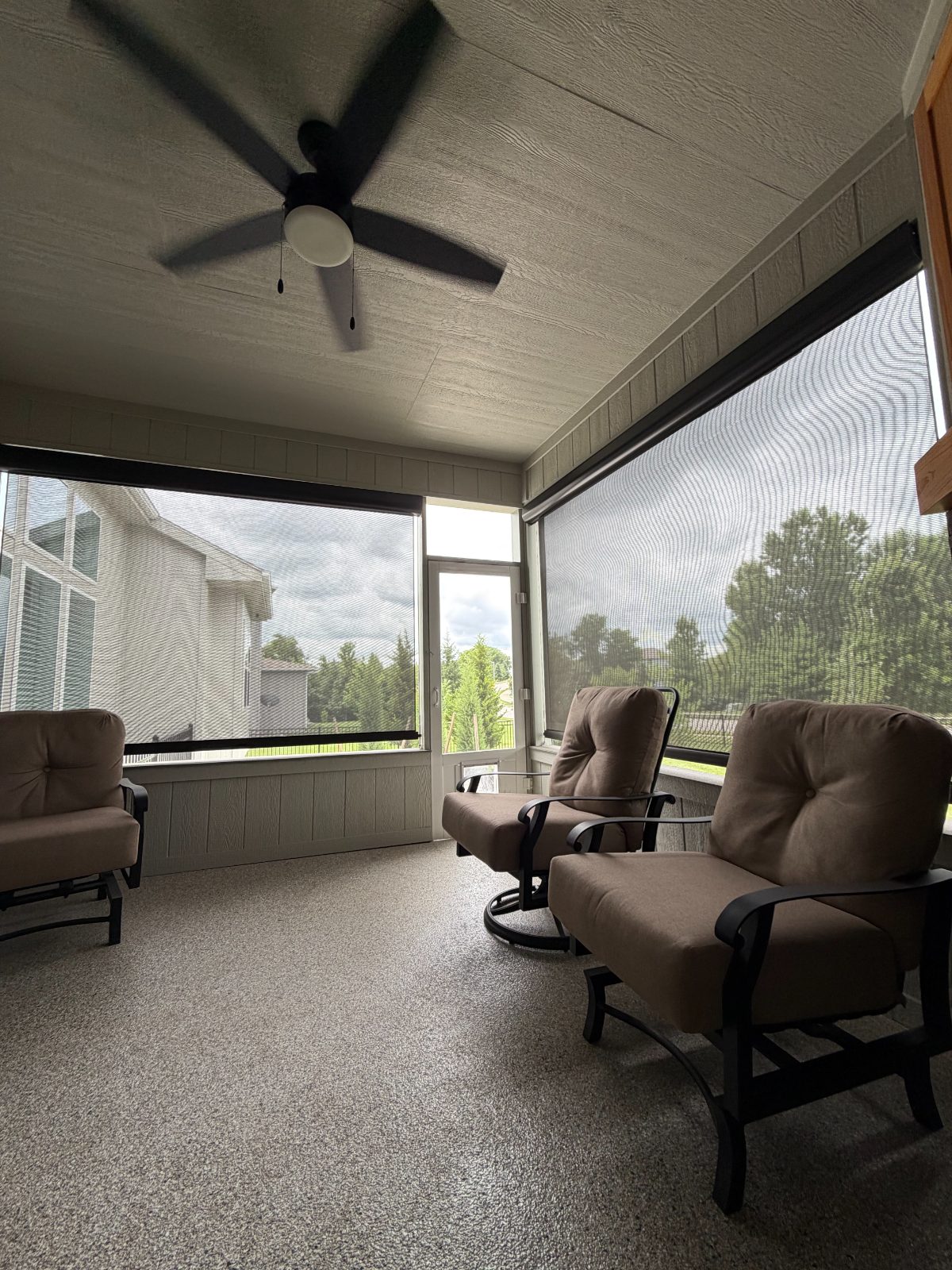Motorized solar screen shades lowered on a covered patio porch to control sun and heat